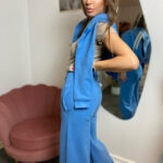 Profil kobiety w błękitnych spodniach dresowych wide leg i bluzie narzuconej na ramiona
