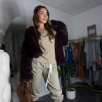 Sensualna kobieta w beżowej koszulce z bawełny organicznej i wysokich brązowych kozakach i kożuchu w kolorze czerwonego wina – styl minimalistyczny