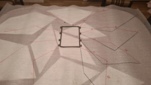 Wycięte elementy skrzydeł ułożone na połyskującym zielonym materiale.