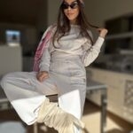 Kobieta w komplecie dresowym łamana biel na tle nieba, lifestylowa stylizacja urban boho