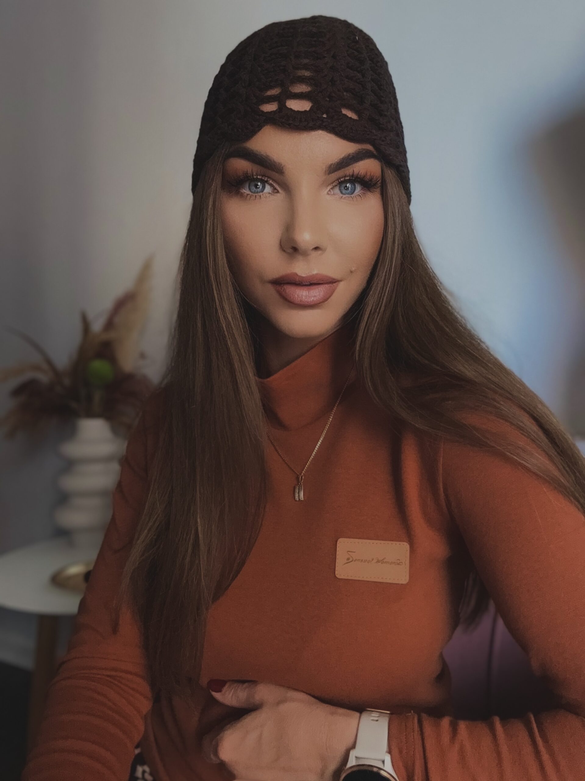 Kobieta w dopasowanym cynamonowym golfie z miękkiej dzianiny ze stójką i naszywką Sensual Woman w jesiennej stylizacji.